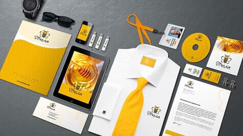 Gold and black brand identity on a shirt, tie, tablet and stationery
