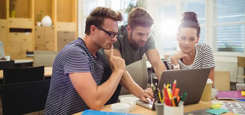 Designers collaborating on a laptop at a shared desk